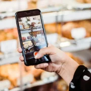 A woman using her phone camera to take a picture of baked goods.