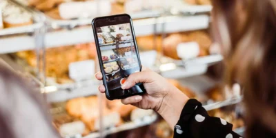 A woman using her phone camera to take a picture of baked goods.
