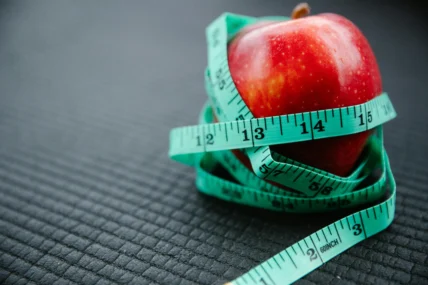 An apple wrapped in a measuring tape.