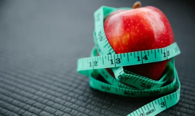 An apple wrapped in a measuring tape.