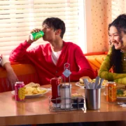 Young people sitting at a table drinking Poppi (Super Bowl commercial)