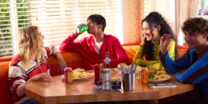 Young people sitting at a table drinking Poppi (Super Bowl commercial)