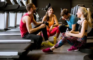 women and man talk near treadmills after a workout