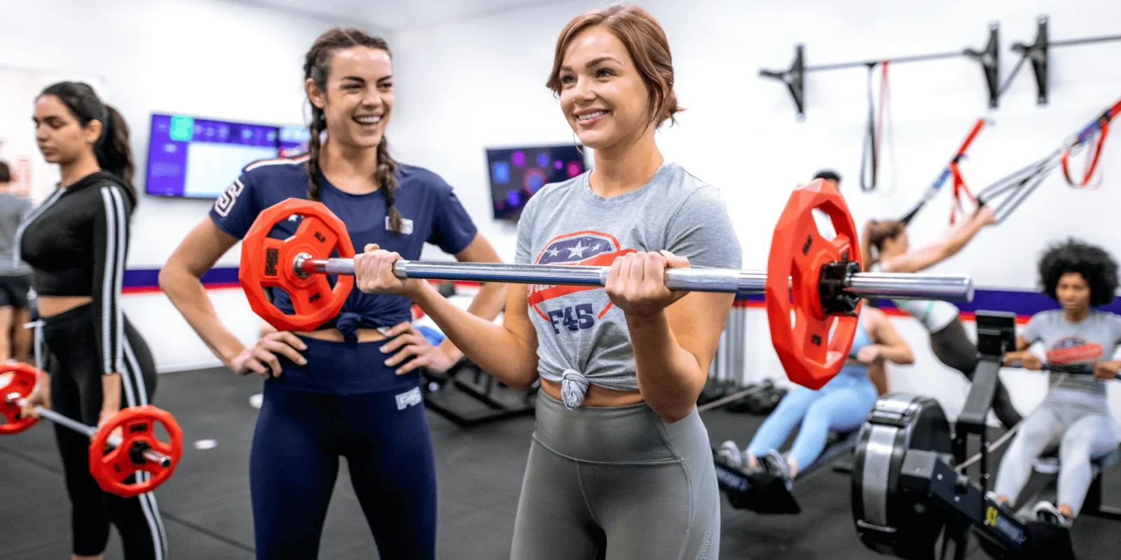 Two women working out at F45 with a barbell