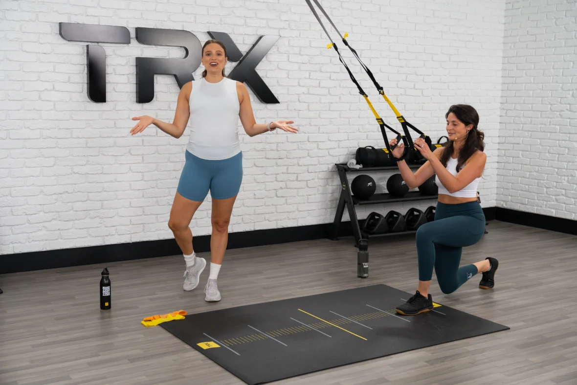TRX new training program for prenatal and postnatal women. Image depicts a trainer and a woman using TRX straps.