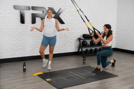 TRX new training program for prenatal and postnatal women. Image depicts a trainer and a woman using TRX straps.