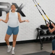 TRX new training program for prenatal and postnatal women. Image depicts a trainer and a woman using TRX straps.