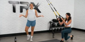 TRX new training program for prenatal and postnatal women. Image depicts a trainer and a woman using TRX straps.