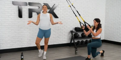 TRX new training program for prenatal and postnatal women. Image depicts a trainer and a woman using TRX straps.