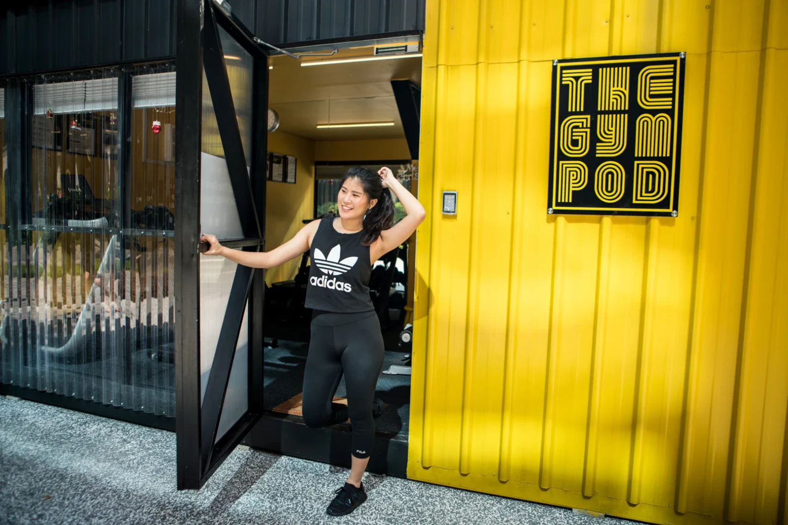 A girl outside of a Gym Pod shopping container in Hong Kong.