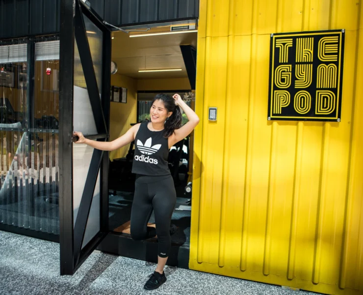 A girl outside of a Gym Pod shopping container in Hong Kong.