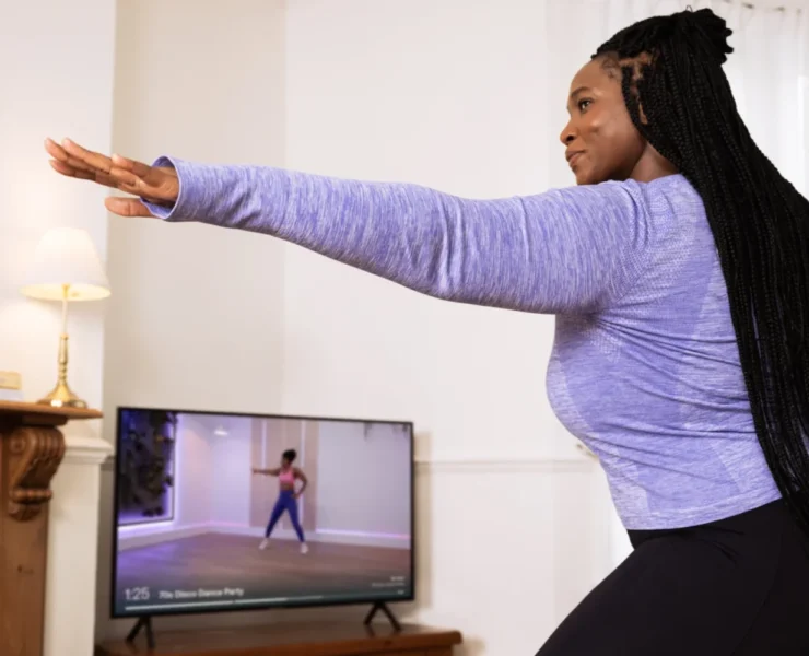 A woman working out in her living room with the guidance of Mvmnt.