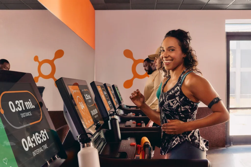 woman runs on a treadmill at an Orangetheory Fitness studio