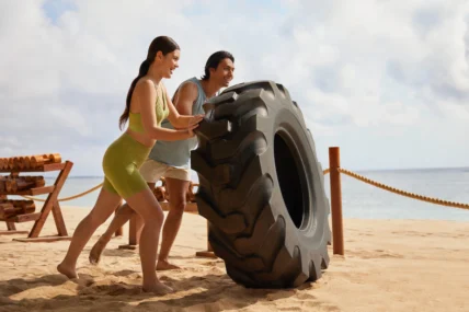 people on beach strength training with a giant tire
