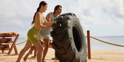 people on beach strength training with a giant tire