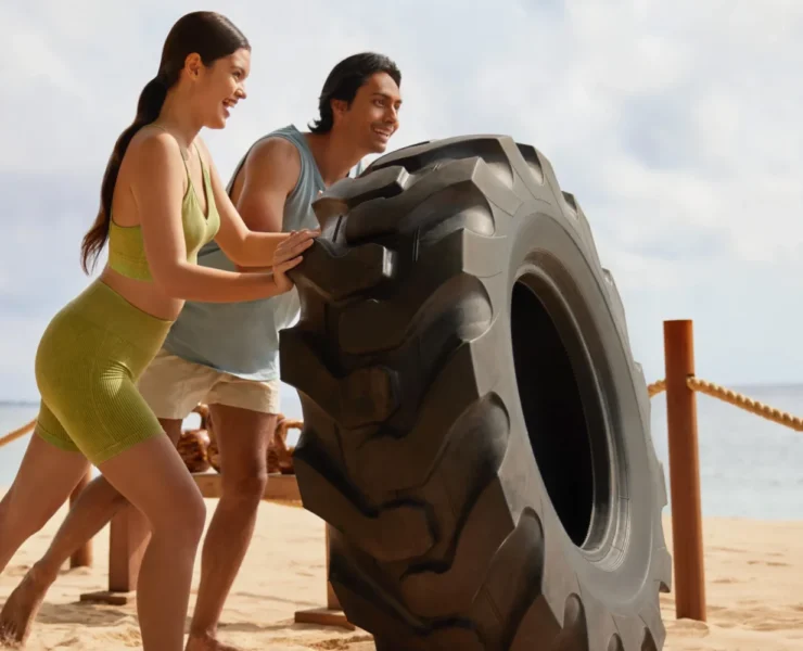people on beach strength training with a giant tire