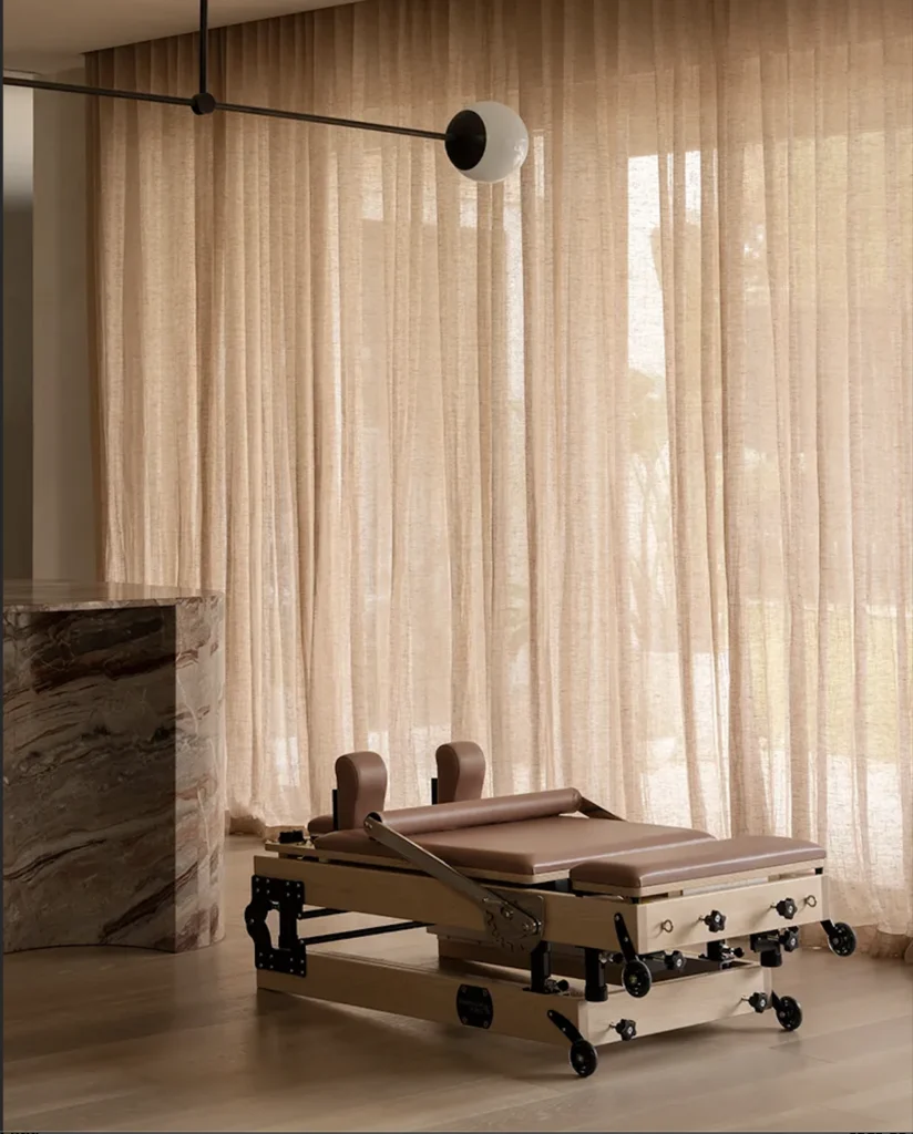 A Pilates reformer machine in a bedroom.