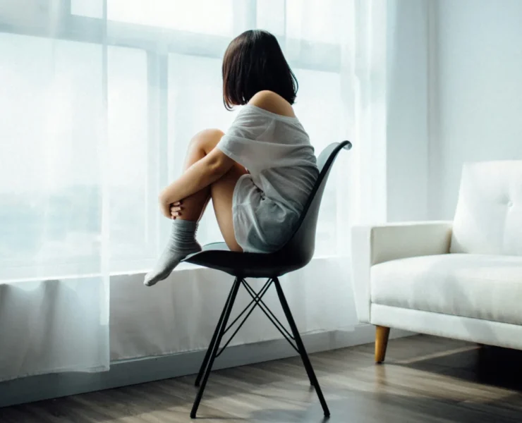 a woman looking out the window giving off morose vibes.