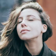 a woman breathing outside, looking relaxed.