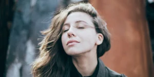 a woman breathing outside, looking relaxed.