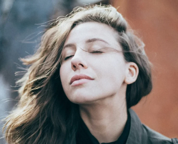 a woman breathing outside, looking relaxed.