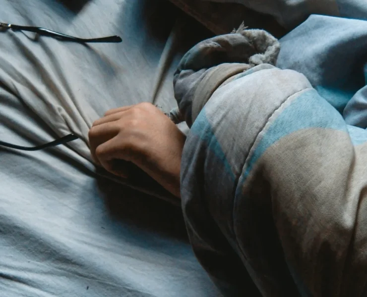 A person sleeping in bed with glasses nearby.