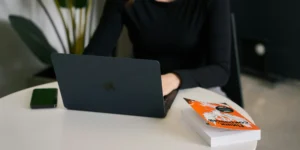 a woman on her laptop with a book nearby.