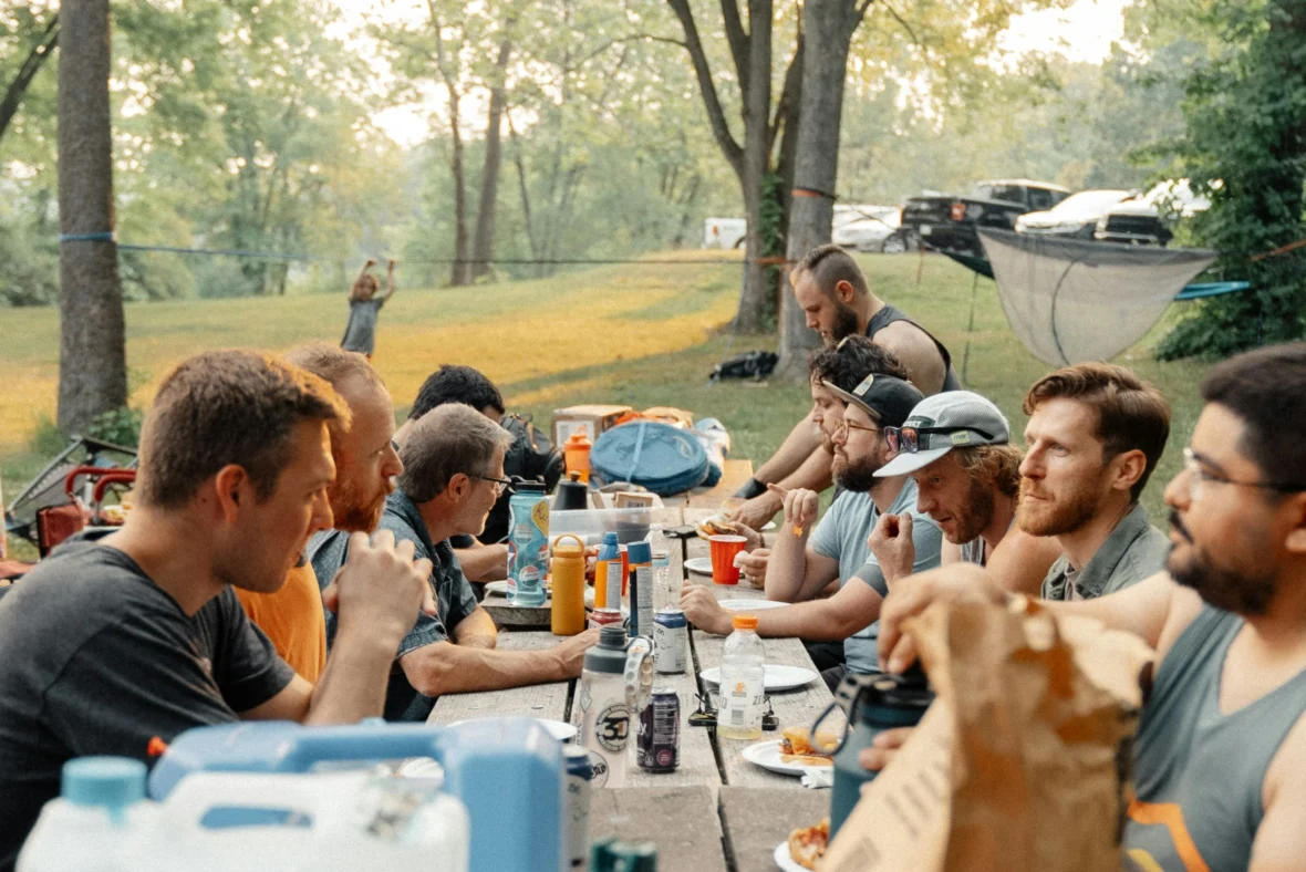 A group of men at a picnic table outside.