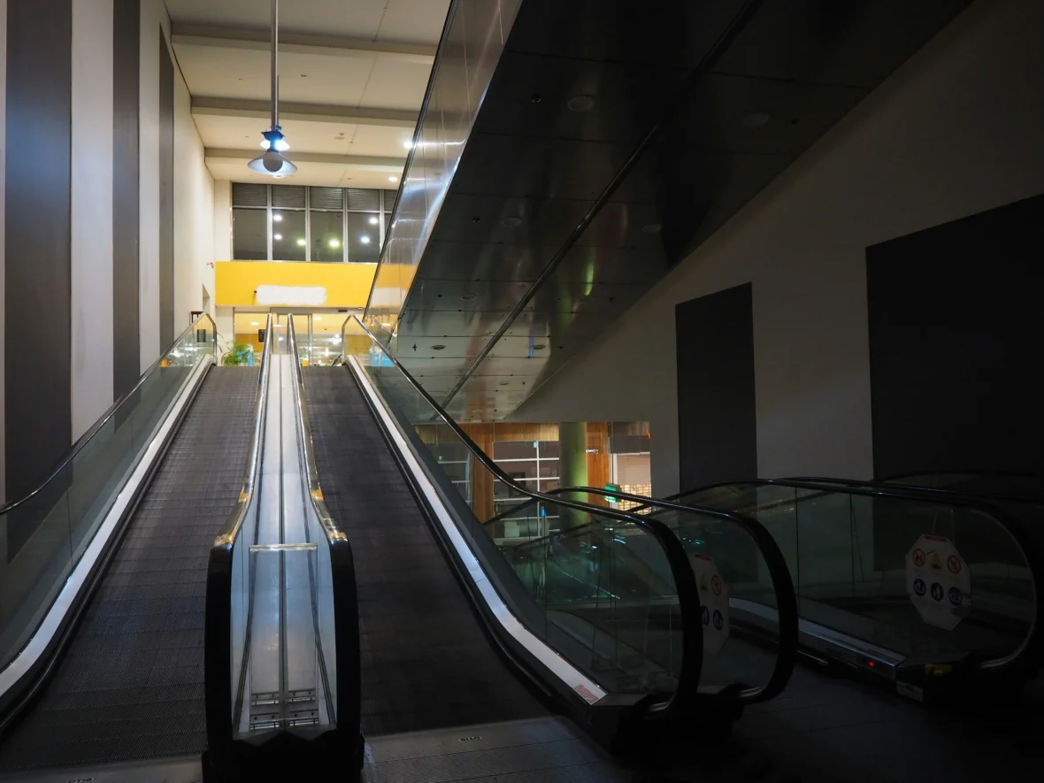 an empty shopping mall with empty escalators.
