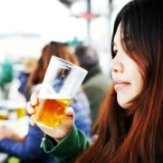 A young woman drinking a beer in a glass.