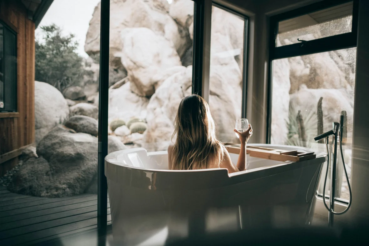 A woman sitting in a tub holding a glass of wine.