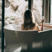 A woman sitting in a tub holding a glass of wine.