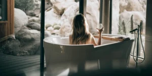A woman sitting in a tub holding a glass of wine.