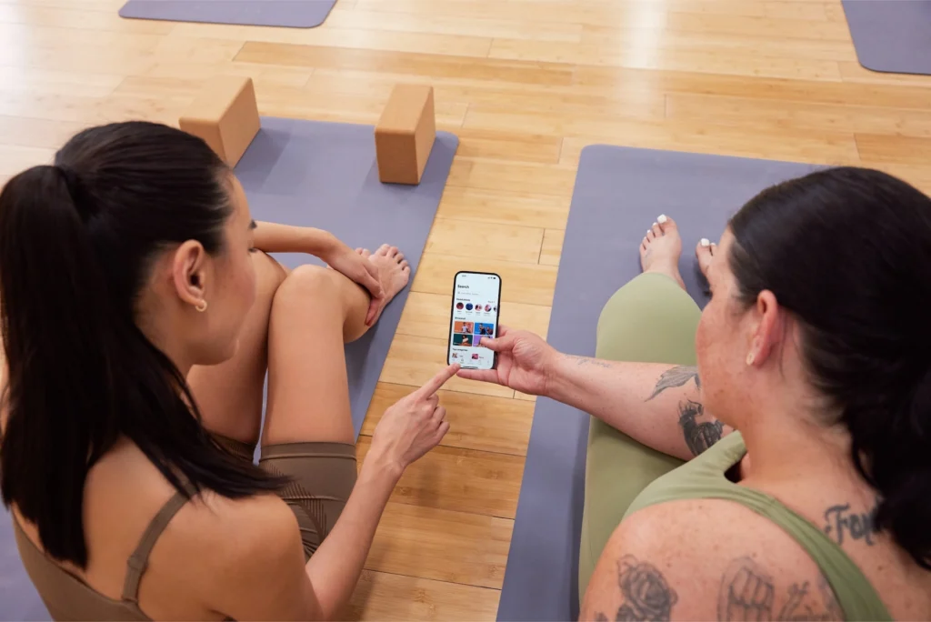 women search for fitness classes on a cell phone