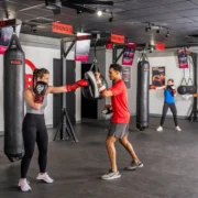 man and women box inside a fitness studio