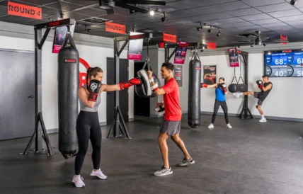 man and women box inside a fitness studio