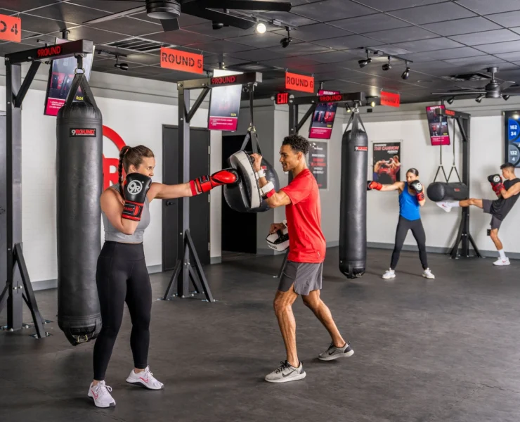 man and women box inside a fitness studio
