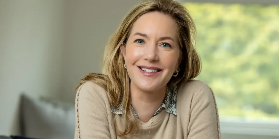 A smiling headshot of Alexia Brue sitting on a chair.