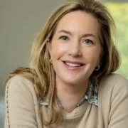 A smiling headshot of Alexia Brue sitting on a chair.
