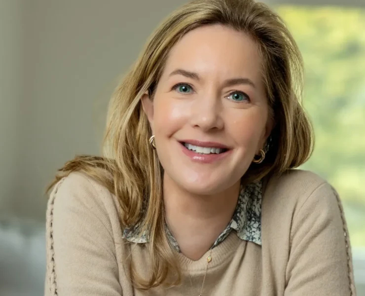 A smiling headshot of Alexia Brue sitting on a chair.