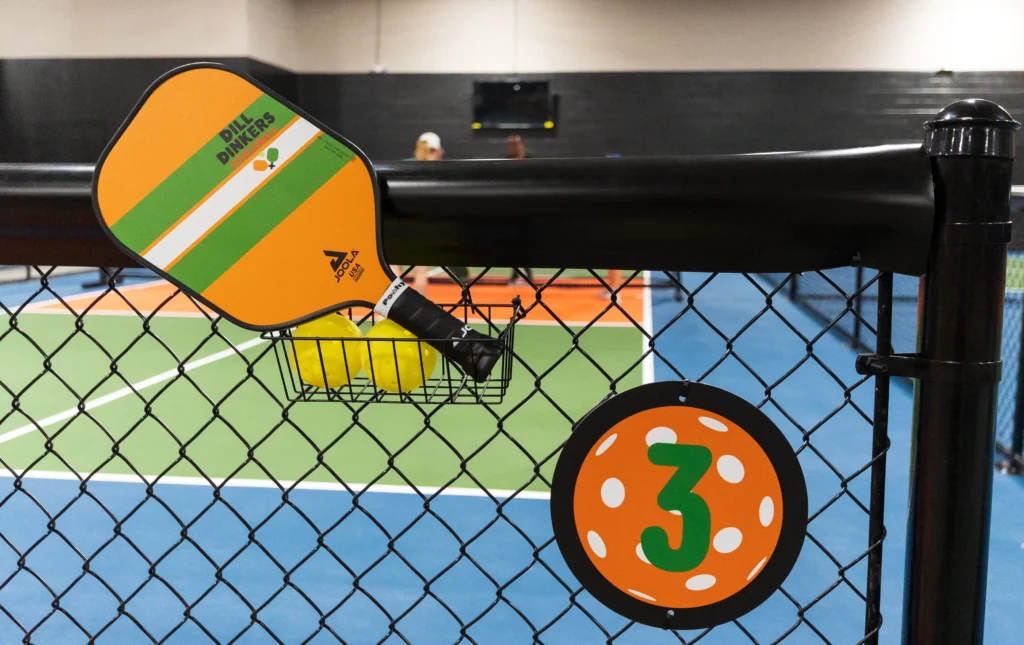 A pickleball paddle and a court in the background at Dill Dinkers.