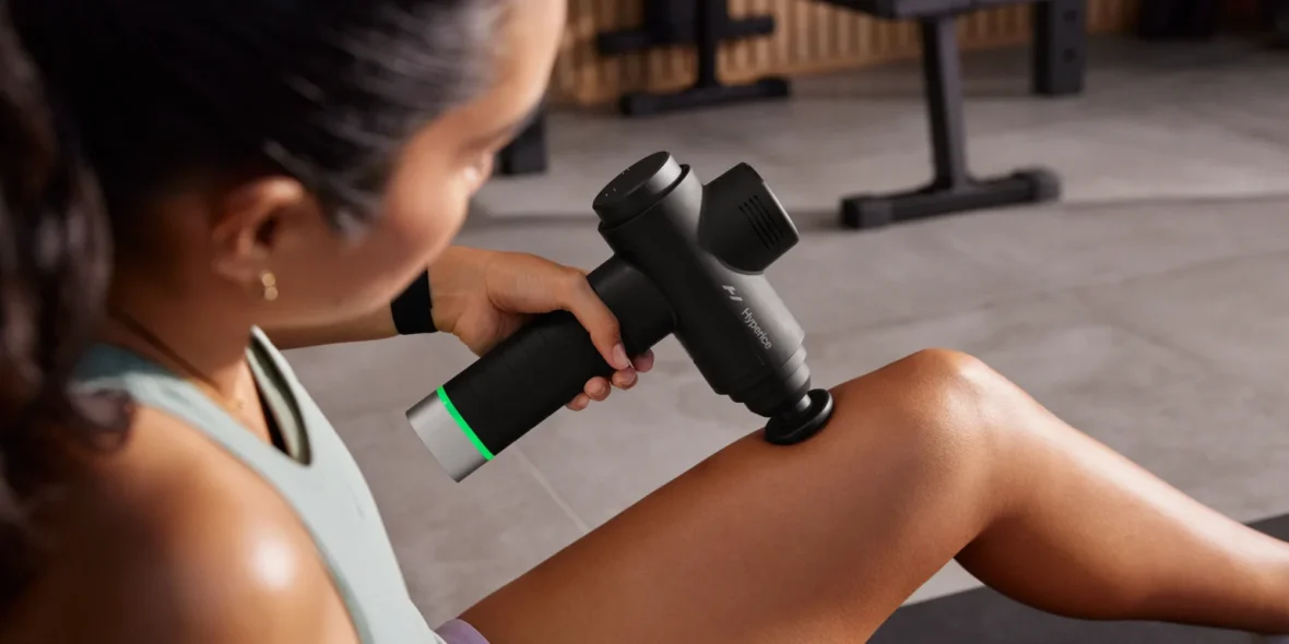 A woman using a Hypervolt device on her leg.