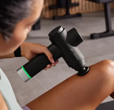 A woman using a Hypervolt device on her leg.