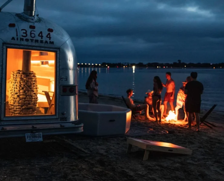 A group of people at the beach enjoying Swet's mobile sauna.