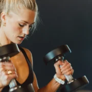 A woman wearing a Second Wind Nasal strip while lifting weights.