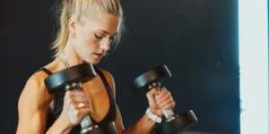 A woman wearing a Second Wind Nasal strip while lifting weights.