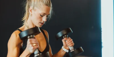A woman wearing a Second Wind Nasal strip while lifting weights.