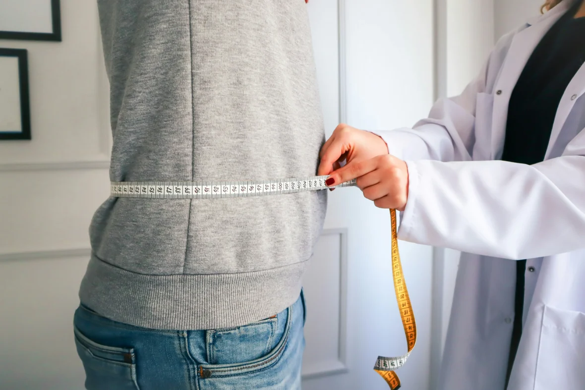 A doctor measuring a patient's waist.