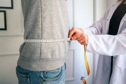 A doctor measuring a patient's waist.