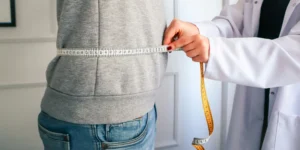 A doctor measuring a patient's waist.